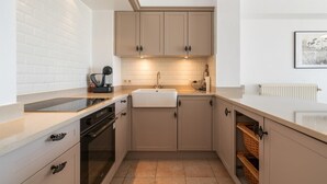 Eine moderne Küche mit beigen Schränken, einer weißen Arbeitsplatte und einem eingebauten Backofen.