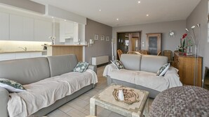 A modern living room with two sofas, a coffee table, and a kitchen area in the background. - Apartment in Blankenberge by the Marina (BLANKENBERGE)