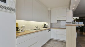 A modern kitchen with white cabinetry, a wooden countertop, and a built-in microwave. - Apartment in Blankenberge by the Marina (BLANKENBERGE)