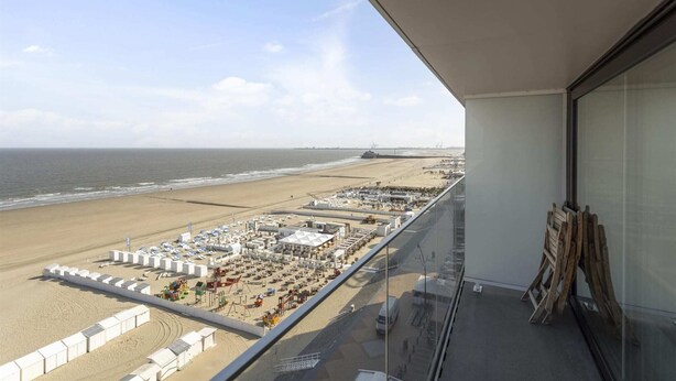 A balcony with a view of a beach and a port.