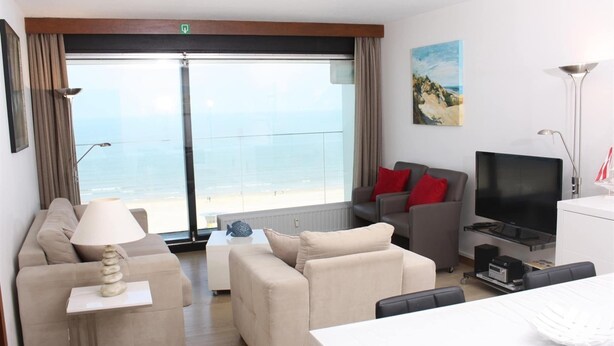 Une chambre d’hôtel moderne dotée d’un grand balcon, d’un canapé, d’une télévision et d’un coin repas.