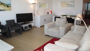 Un salon moderne avec un téléviseur à écran plat, un canapé, une table basse et un tapis rouge.