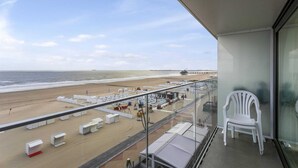 Un balcón con vista a la playa, que incluye sillones de baño y sombrillas.