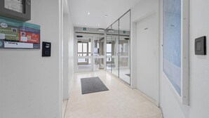 A modern hallway with glass doors, a digital display, and a welcome sign.