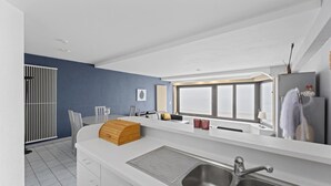A modern kitchen with a white countertop, stainless steel sink, and a large window providing natural light.