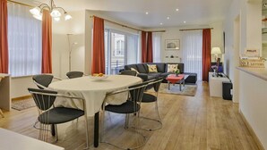 A modern living room with a dining area, a sofa set, and a reception desk. - Apartment in Blankenberge near Seafront (BLANKENBERGE)