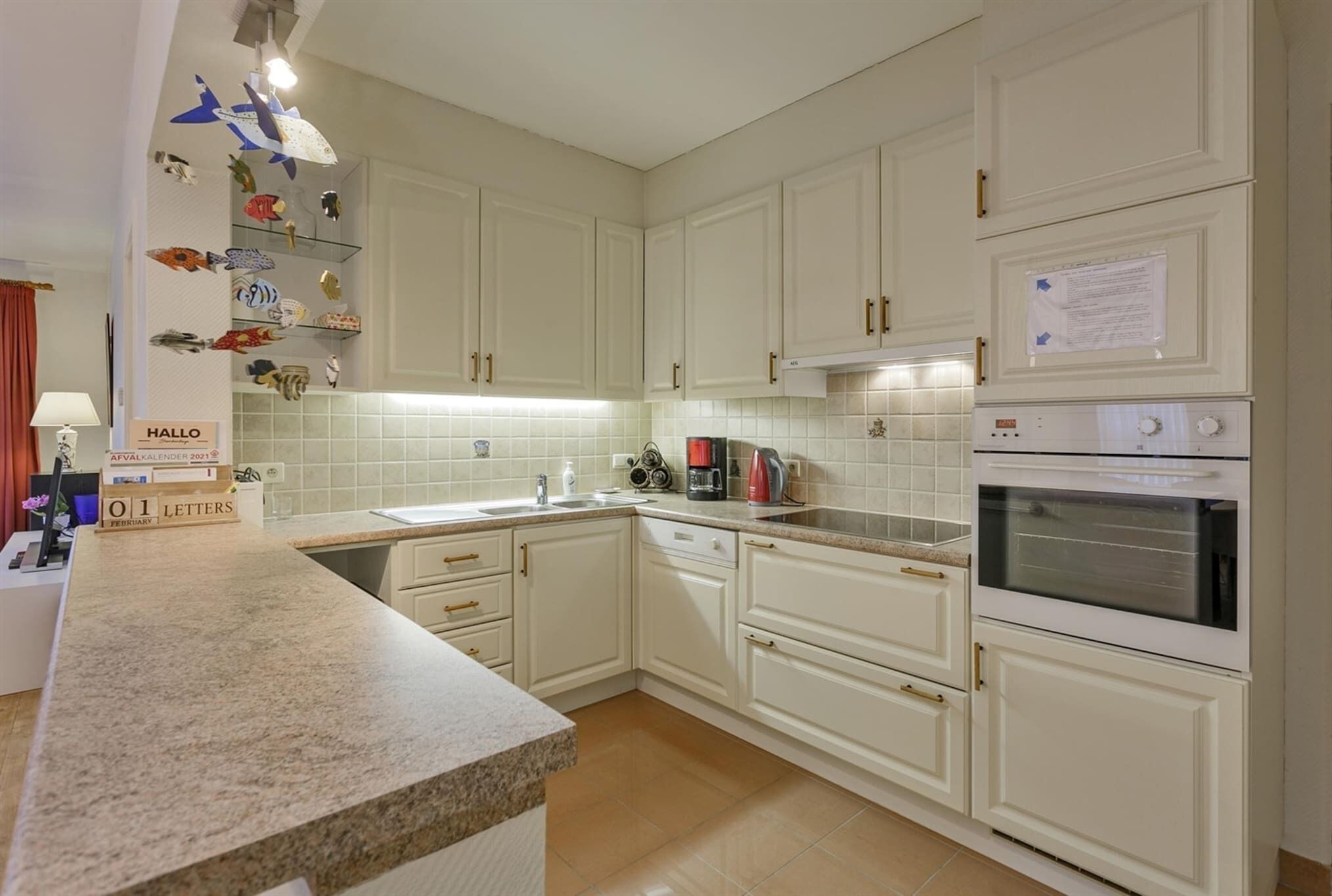 A kitchen with white cabinets, a granite countertop, a coffee maker, and a clock.