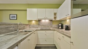A compact kitchen with white cabinets, a wooden countertop, and a sink.