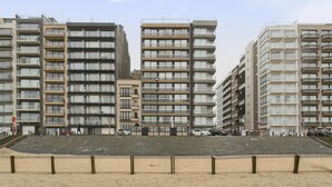 A beachfront hotel with multiple high-rise buildings, balconies, and a sandy beach area.