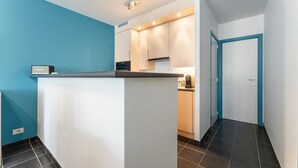 A compact kitchen with a central island, a built-in oven, and a coffee machine.