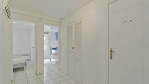 A hallway with a white door, a bench, and a view into another room. - Apartment in Blankenberge with Sea Views (BLANKENBERGE)