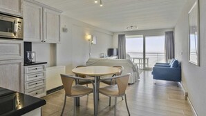 A modern hotel room with a kitchen, dining area, and a balcony with a view. - Apartment in Blankenberge with Sea Views (BLANKENBERGE)