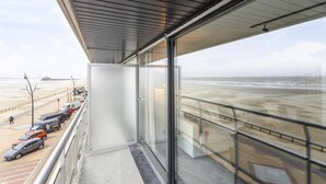 A balcony with a view of the beach and parked cars. - Studio in Blankenberge with Stunning Sea View (BLANKENBERGE)