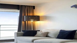 A modern living room with a sofa, a lamp, and a view of the outdoors. - Studio in Blankenberge with Stunning Sea View (BLANKENBERGE)