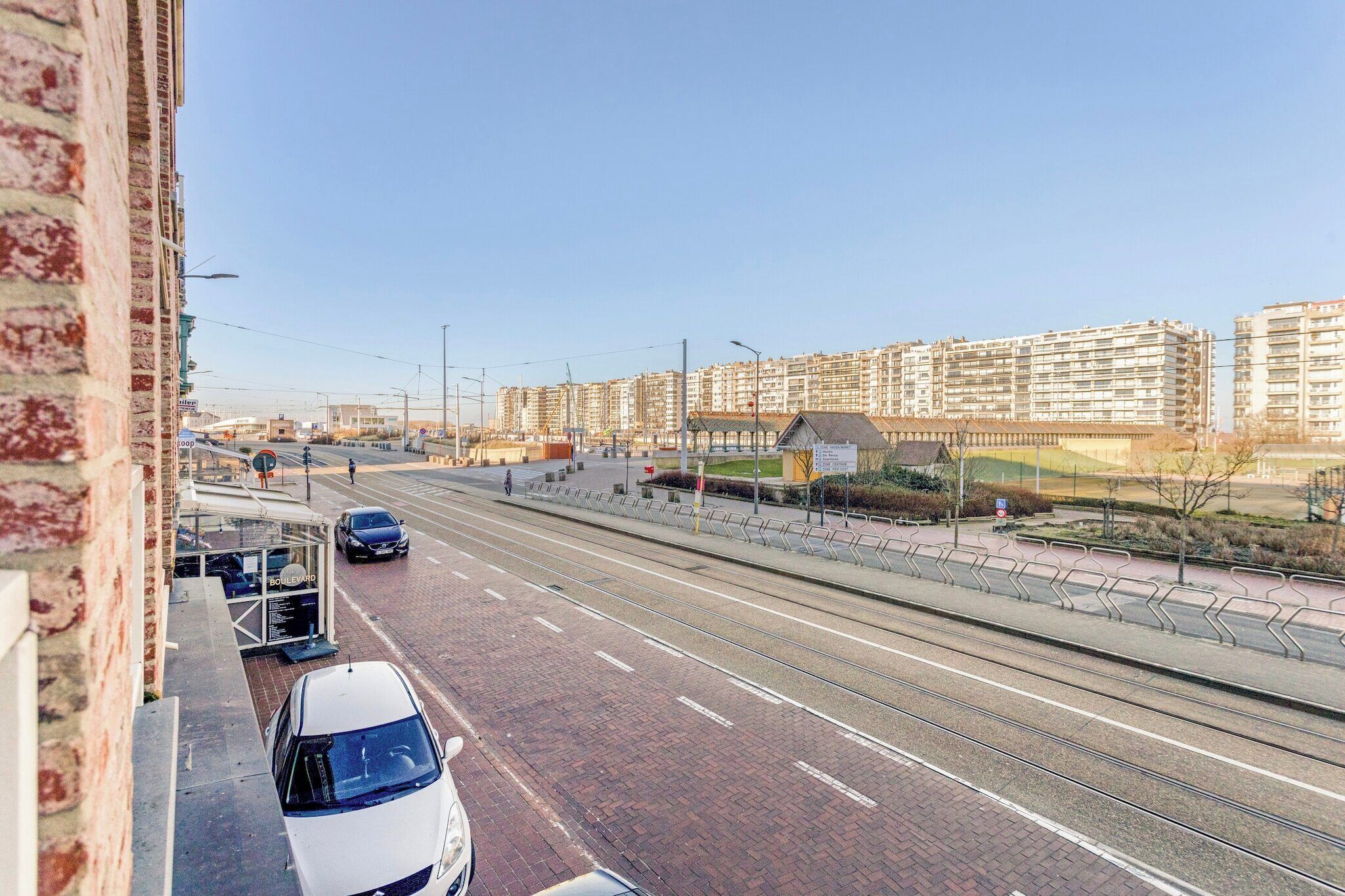 A street with tram tracks, a white car, and a building with a sign that reads "Boulangerie".