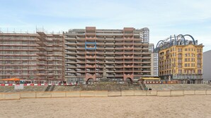 A multi-story building with a modern architectural design, featuring a prominent central column and a series of balconies. - Apartment in Blankenberge with Sea Views (BLANKENBERGE)