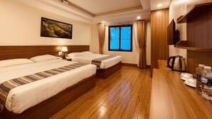 A hotel room with two beds, a wooden floor, a painting on the wall, a window with curtains, and a coffee maker on the side table. - SaPa Marigold Hotel (Sa Pa)