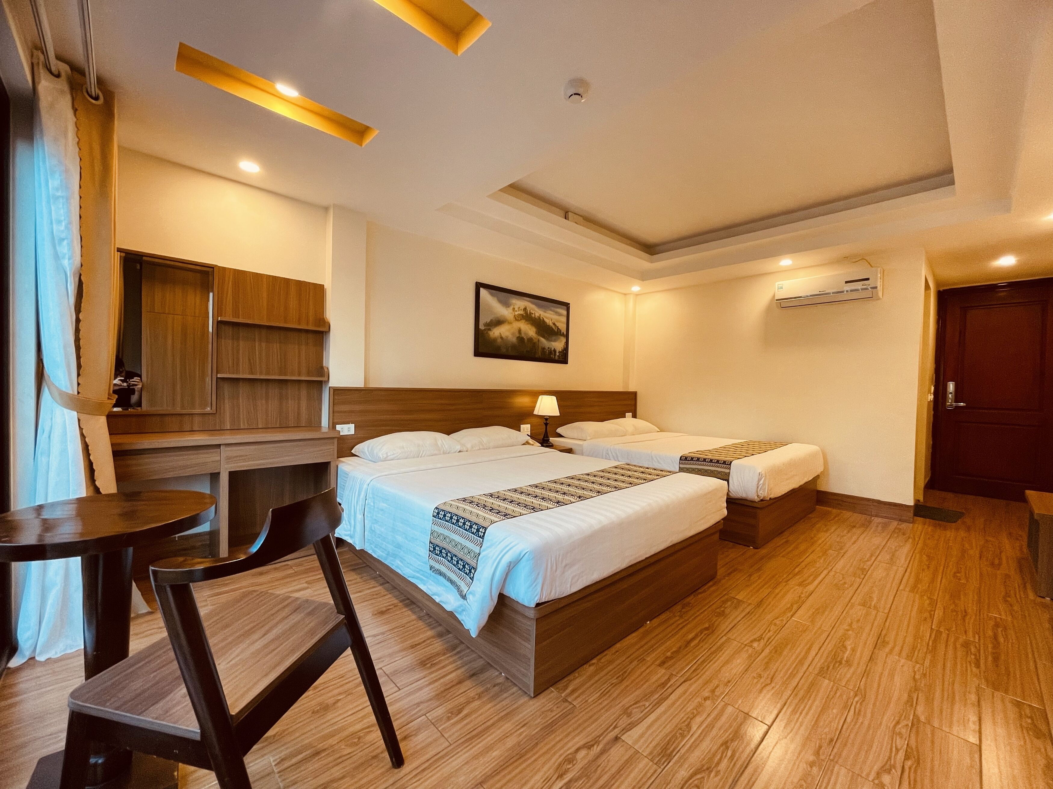 A hotel room with two beds, a desk, a chair, a mirror, and a painting on the wall.