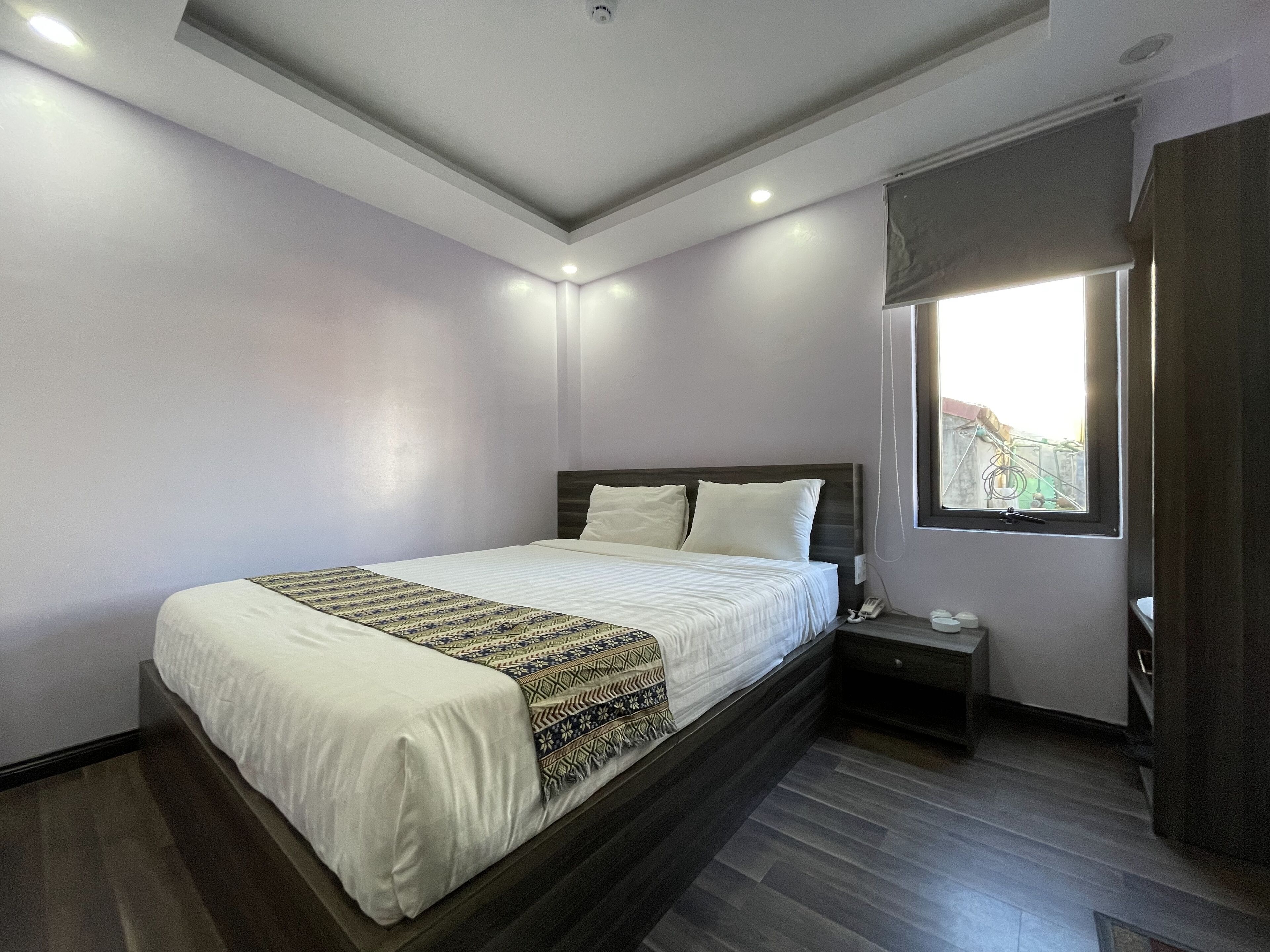 A bedroom with a bed, bedside table, and a window.