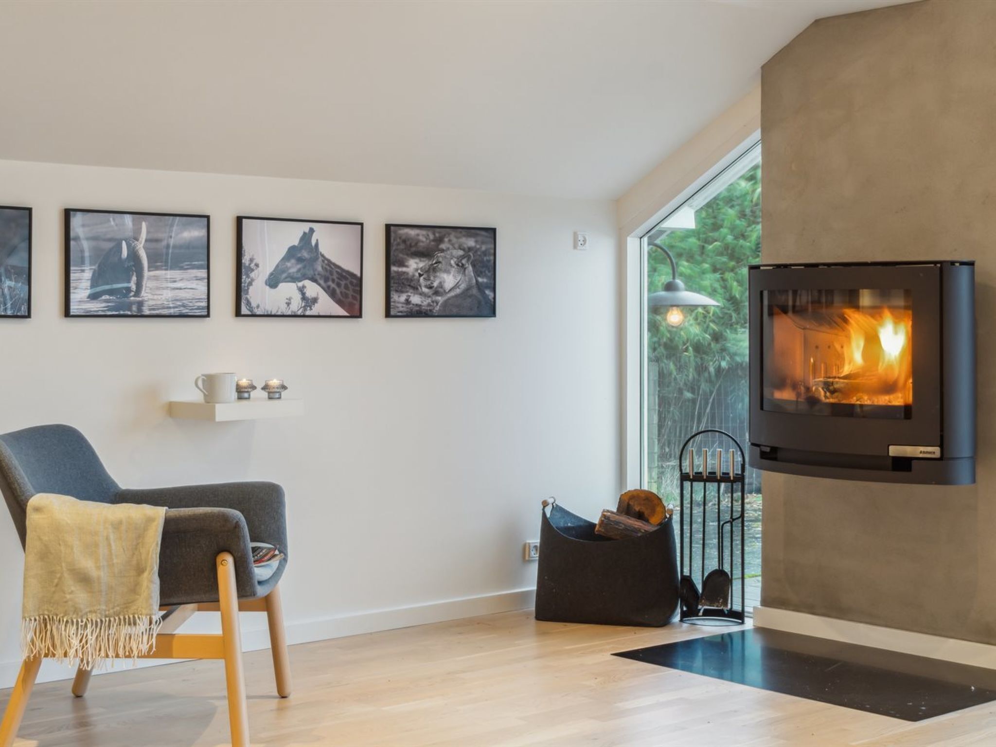 Una sala de estar moderna con chimenea, un sofá gris y fotografías enmarcadas de fauna en la pared.