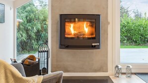 A modern living room with a built-in fireplace, a comfortable sofa, and a view of the outdoors. - "Frithlef" - 1.3km from the sea by Interhome (Græsted)
