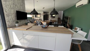 A modern kitchen with a central island, white cabinetry, and a large window. - Villa with swimming pool and Jacuzzi, ideal for families, beach 10 min away, residential (La Crau)