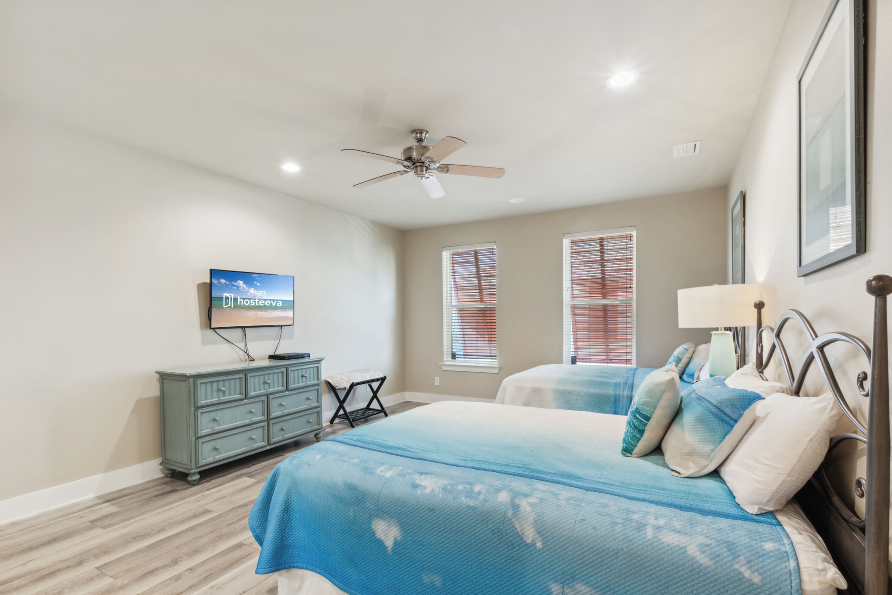 A bedroom with a bed, a dresser, a television, and a ceiling fan.
