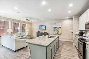 A spacious kitchen with a central island, wooden flooring, and a ceiling fan. - Bottlenose Beach House (Gulf Shores)