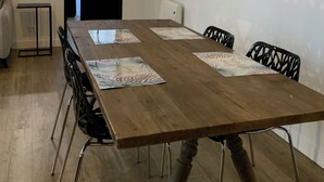 Un comedor con una mesa de madera, sillas negras y un espejo grande en la pared.