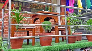 Modelo de un vestíbulo de hotel con pared de ladrillo, mobiliario de madera y plantas en macetas.