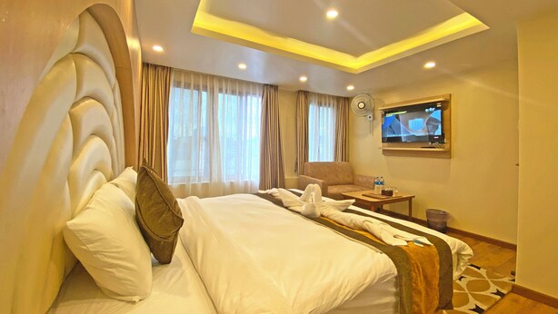 Habitación de hotel con una cama grande, un televisor en la pared y un ventilador de techo.