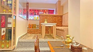 Una habitación de hotel acogedora con una pared de ladrillo decorativa, una zona de comedor con una mesa dispuesta para dos personas y una estantería llena de libros y botellas.
