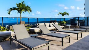 A rooftop lounge area with sun loungers and a view of the ocean. - Way Tambaú  (João Pessoa)