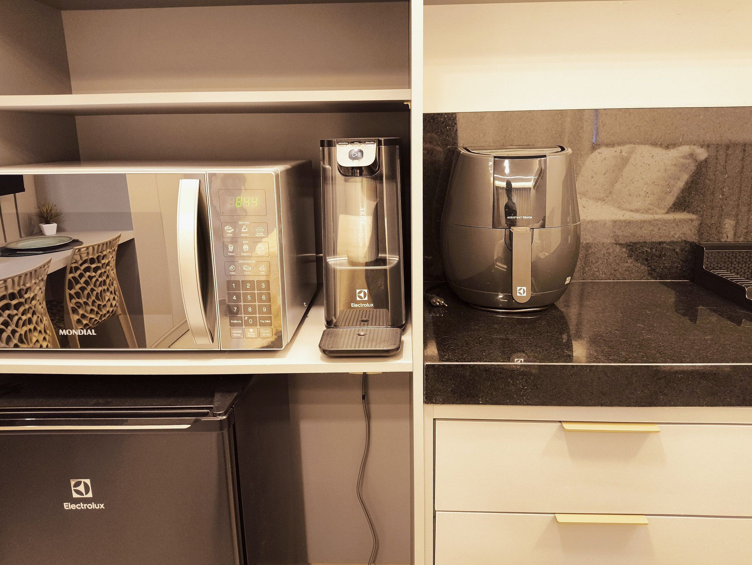 Uma cozinha compacta equipada com micro-ondas, cafeteira e frigorífico.