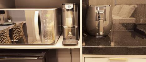 Uma cozinha compacta equipada com micro-ondas, cafeteira e frigorífico.