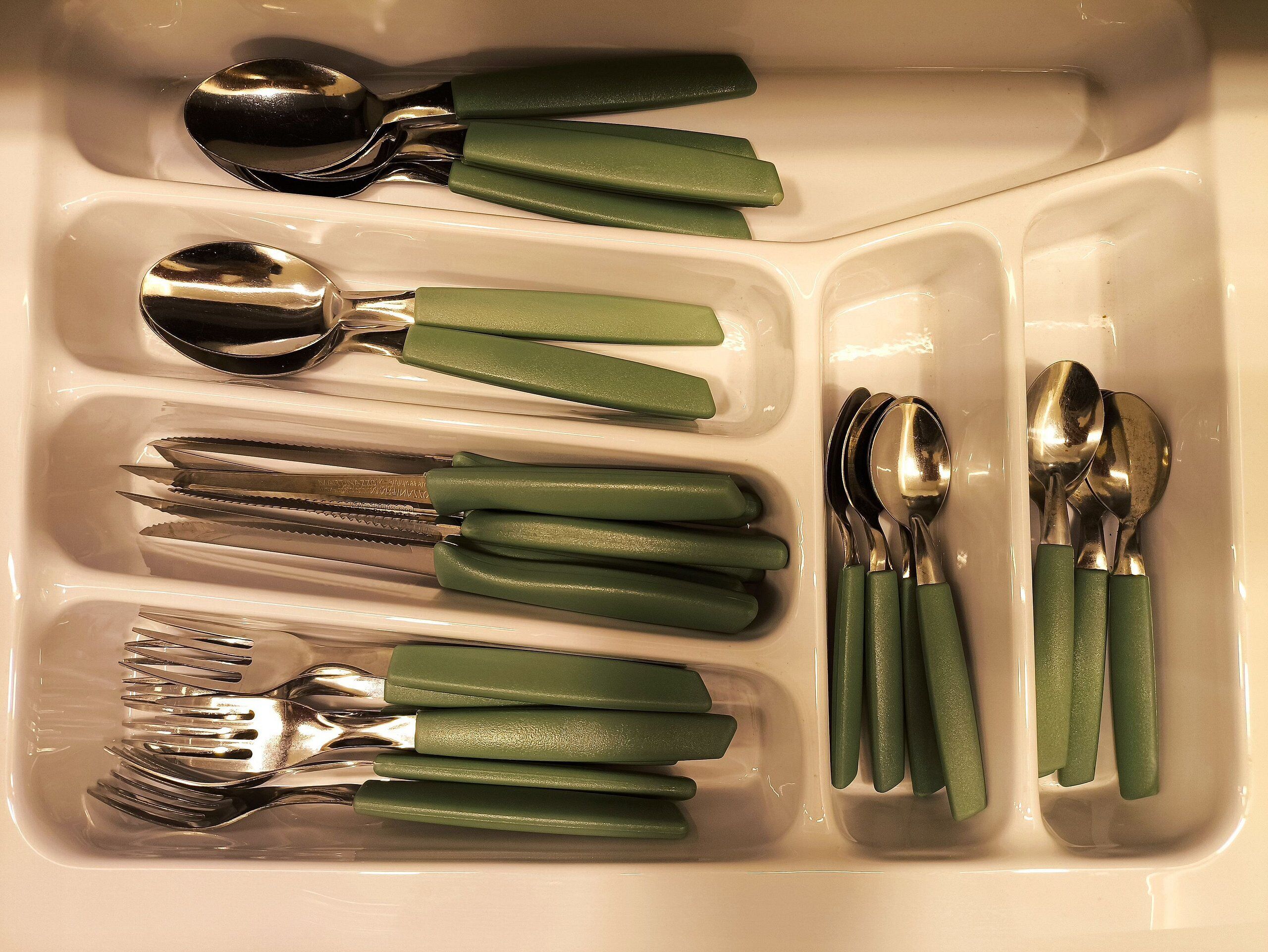 A kitchen sink with various utensils neatly arranged in compartments.