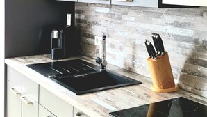 A modern kitchen with grey cabinets, a black sink, and a built-in stove.