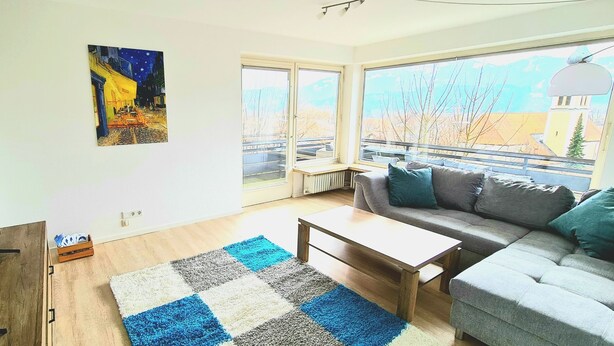 Ett modernt vardagsrum med ett stort fönster, en platt-TV, en soffa och ett soffbord.