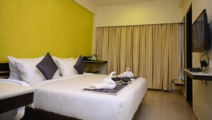 Ein Hotelzimmer mit Bett, Nachttisch, Fernseher und einem Fenster mit Vorhängen.