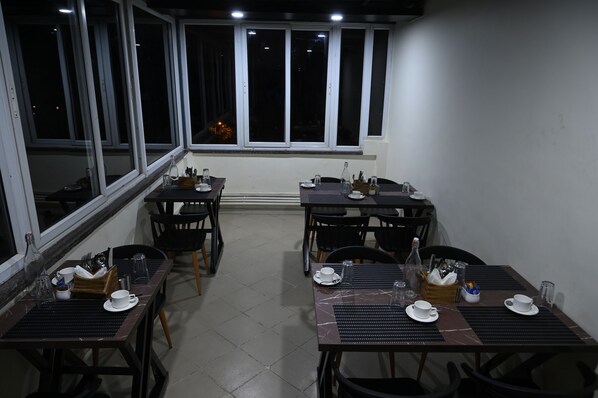 A dining area with tables set for two, equipped with cutlery, glasses, and plates. - Rajkiyam - A Business Hotel (Bengaluru)