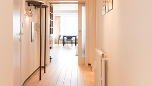 Een hal met houten vloer, een radiator en ingelijste foto's aan de muur.