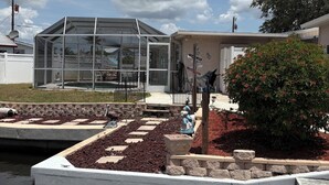 Un bâtiment moderne doté d’une structure en verre évoquant une serre, d’un chemin pavé et d’un jardin aménagé avec un petit étang.