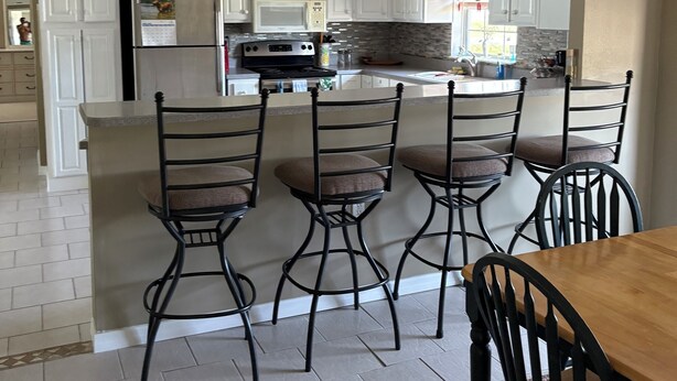 Une cuisine moderne avec des meubles blancs, un réfrigérateur, un four à micro-ondes et un coin repas comprenant une table en bois et quatre chaises.