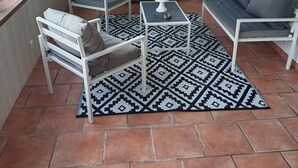 Ein sonnendurchfluteter Raum mit Fernseher, zwei Sofas, einem Couchtisch und einem gemusterten Teppich.