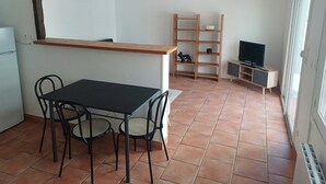 Eine kompakte Küche mit Esstisch und Stühlen, einem Holzbodenregal und einem Fernseher auf einem Tisch.