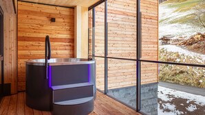 Un sauna avec un intérieur en bois et une vue sur un paysage enneigé, visible à travers de grandes fenêtres.