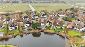 Een dorp met traditionele huizen, een vijver en een weg naar een grotere stad.