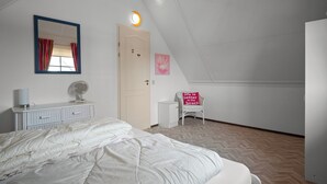 Een slaapkamer met een bed, een kaptafel, een spiegel en een stoel met een motiverende quote.