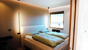 A modern bedroom with a large bed, a window with a view, and a minimalist design. - SeeZeit at Walchsee (Walchsee)