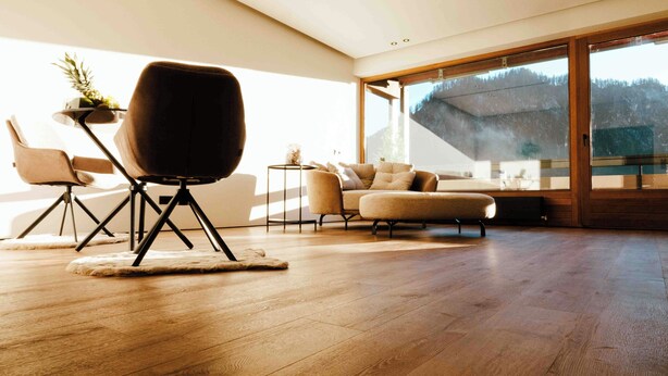 A spacious living room with a large window, a modern sofa, a chair, and a small table. - SeeZeit at Walchsee (Walchsee)